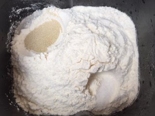 花朵豆沙面包,然后，再把面包粉，加入进去；再两个对角，分别放入酵母和盐，分开放置，以免影响了酵母的作用；
