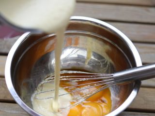  杏仁乳酪蛋糕,把搅拌好的乳酪糊倒进蛋黄中搅拌均匀。「此时已不用在隔热水搅拌！！！」