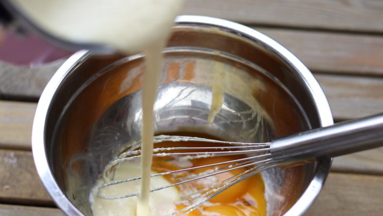  杏仁乳酪蛋糕,把搅拌好的乳酪糊倒进蛋黄中搅拌均匀。「此时已不用在隔热水搅拌！！！」