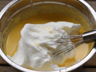  杏仁乳酪蛋糕,取三分之一拌入蛋黄糊中！翻拌均匀。