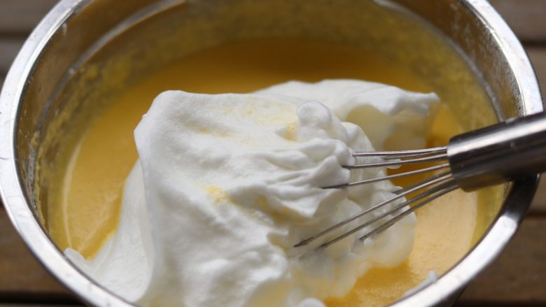  杏仁乳酪蛋糕,取三分之一拌入蛋黄糊中！翻拌均匀。