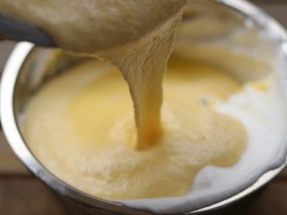  杏仁乳酪蛋糕,把翻拌好的蛋黄糊倒入剩下的蛋清中继续翻拌。