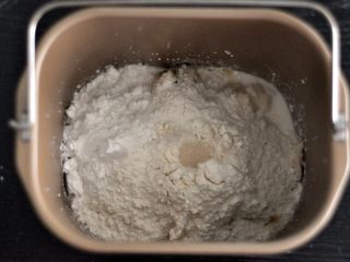 黑芝麻吐司,将面粉覆盖在液体之上，对角分别上放上盐和糖，在面粉中间挖一个小坑，放上酵母。