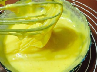 百香果酱香玛德琳,黄油小火加热融化倒进蛋黄糊里快速搅拌均匀。搅拌好的面糊呈飘带状。