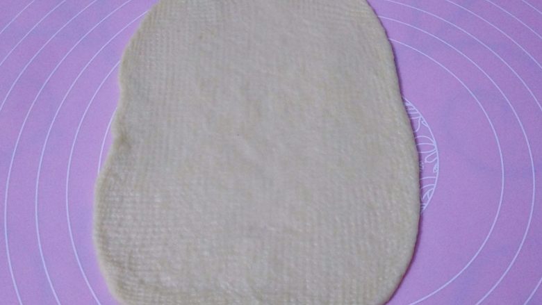 香葱芝士面包,取一个面团擀成长方形，松弛过的面团比较容易擀，觉得不太好擀的可以换一面再擀平，宽度不要太长，以超出火腿肠1-2厘米最合适