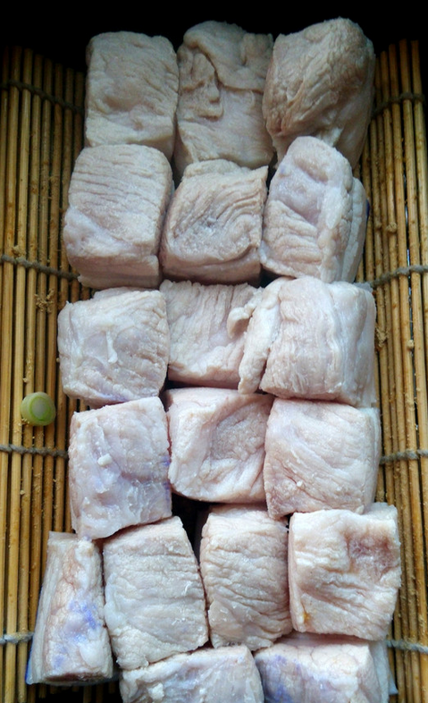 家常东坡肉,大砂锅里用竹箅子垫底，先铺上葱和姜，再将猪五花的皮面朝下，排在上面