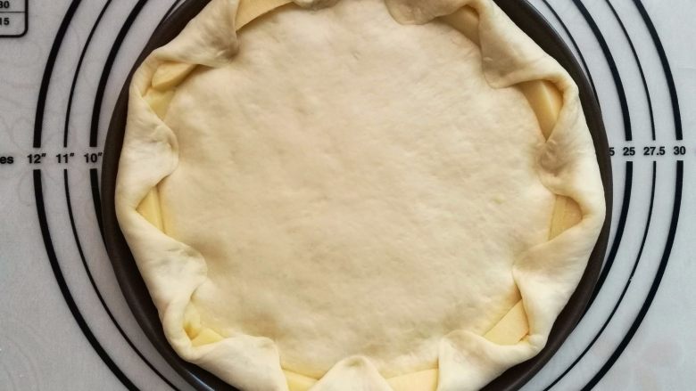 墨鱼热狗芝心披萨,把大出来的饼皮向里折入压紧，包住芝士条。