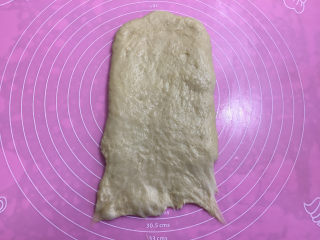面包机版黑钻吐司,取出面团进行排气，然后用擀面杖擀开，翻面后底部按薄。