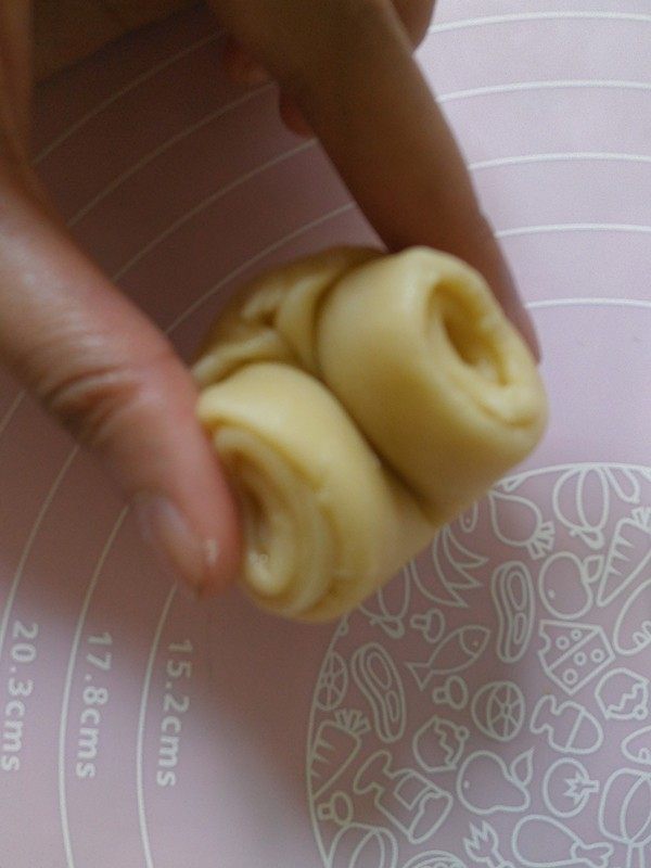 蛋黄酥黄油版,将松弛好的面卷取出用拇指在中间压一下 然后将卷的两端对夹起来