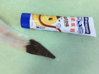 棉花糖淋酱夹心曲奇饼干,巧克力味炼乳装入裱花袋中，剪开一个小口。