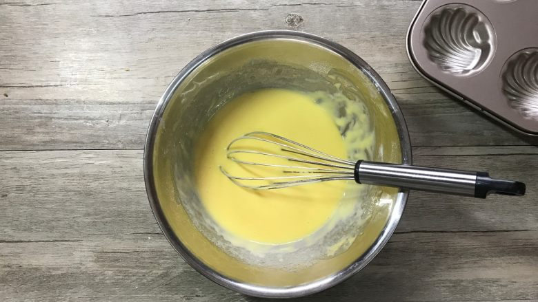 橙香玛德琳,加入事先融化好的黄油，继续之字形搅拌均匀。