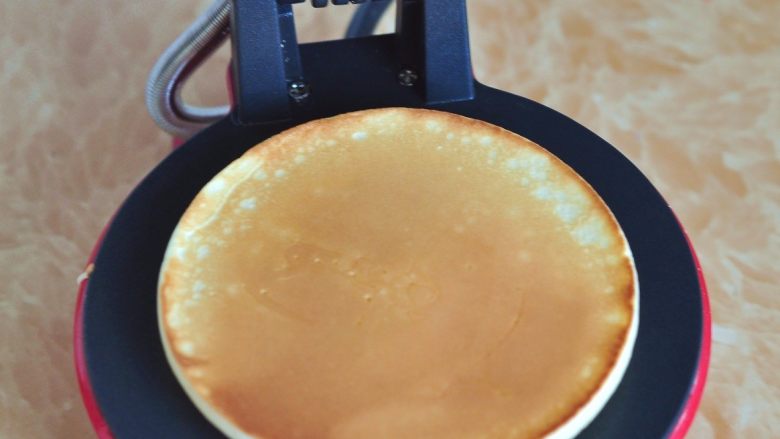 奶油松饼,等表面出现小泡时，已经凝固，翻面将另一面加热几秒。煎好的松饼放一旁备用。直到面糊用完。