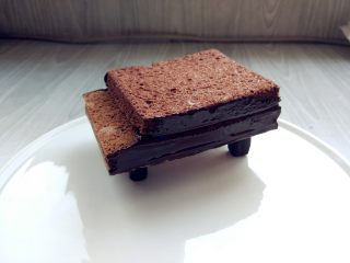 可可钢琴蛋糕,将钢琴支架顶部粘少许黑巧克力，放在盘中合适位置，将钢琴主体放在上面，侧面涂少许巧克力（或甘纳许）