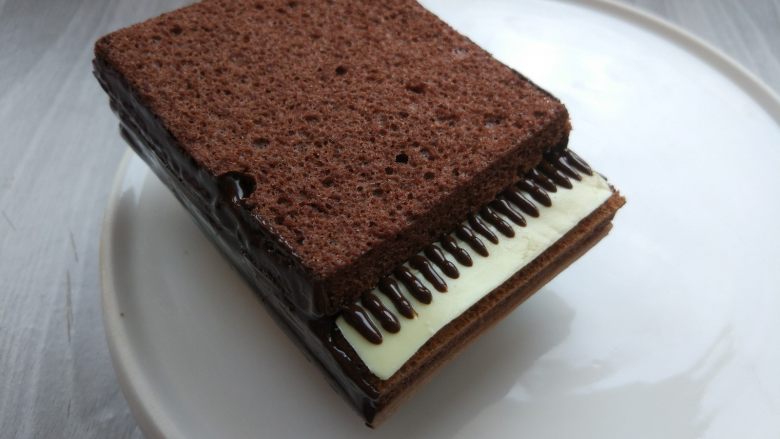 可可钢琴蛋糕,将凝固的白巧克力条放在琴键位置，用黑巧克力画出琴键