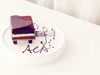 可可钢琴蛋糕,将凝固的钢琴盖放在顶部，一侧用一小块蛋糕体支撑起，另用黑巧克力在盘上画出音符即可