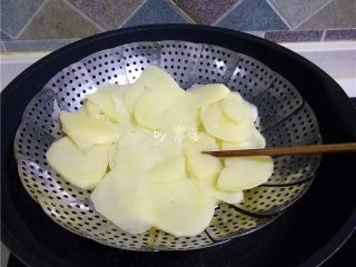 咖喱土豆盖饭,锅里倒入清水烧开，放入蒸片，再放入土豆蒸熟；