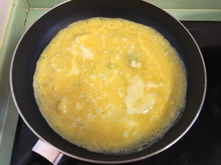 早餐鸡蛋卷,油热后将打散的蛋液倒入锅中，手拿起锅在火上转着将鸡蛋摊匀。