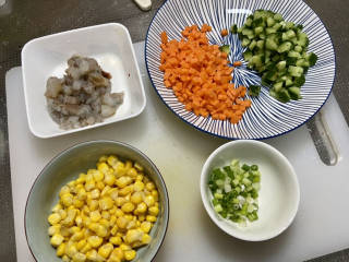 玉米虾仁蛋炒饭,虾仁切小段，胡萝卜切小粒，黄瓜切比胡萝卜大一点的小粒，小葱切末，