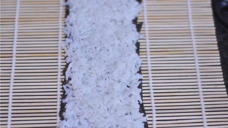 花朵寿司——小朋友最爱哦,另外半片海苔上均匀地摆放上白色米饭，