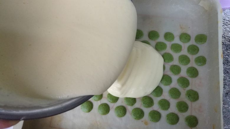 抹茶波点蛋糕卷,在烘烤好的波点上面倒入蛋糊，刮刀抹平。