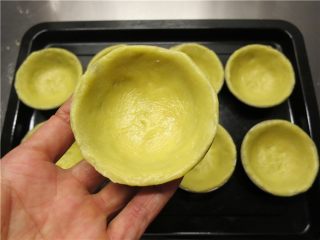 流心芝士挞,用两手的拇指将挞皮面团捏成挞模的形状。厚薄要均匀，边缘要整齐，烤出来的挞才会好看。