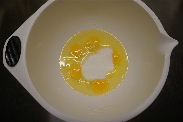 南瓜仁全蛋海绵蛋糕,盆里放进全蛋，一次性加进砂糖、水怡手动打蛋器搅匀打散