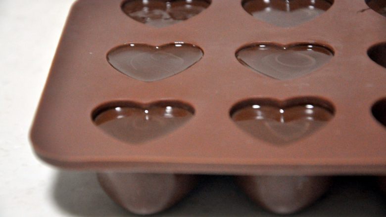 心型调温巧克力,将花嘴剪开一个小口，从模具的底部开始挤，挤好后轻轻震一下模具，震掉气泡。