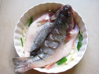 川香麻辣烤鱼：麻辣过瘾的豪华烤鱼,将腌好的鱼放入烤盘中。
