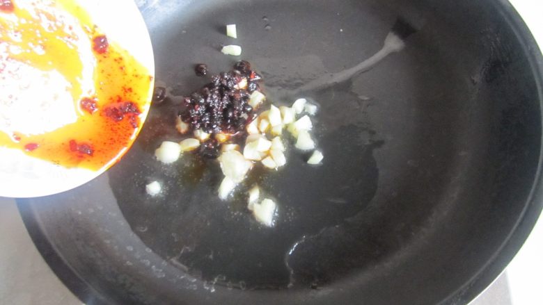 肉末干子炒毛豆米,热锅凉油， 放入蒜末和豆豉酱爆香；