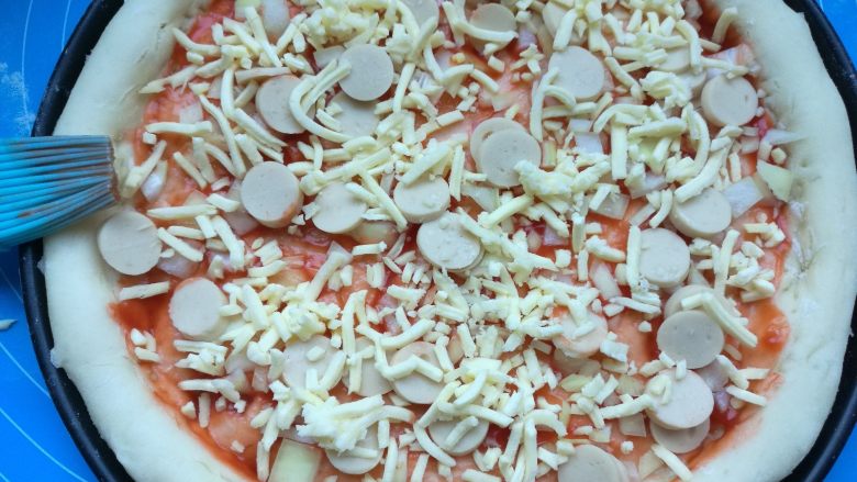 果干鸡肉披萨,刷上披萨酱，洒上几粒小香肠，撒一层马苏里拉芝士碎。