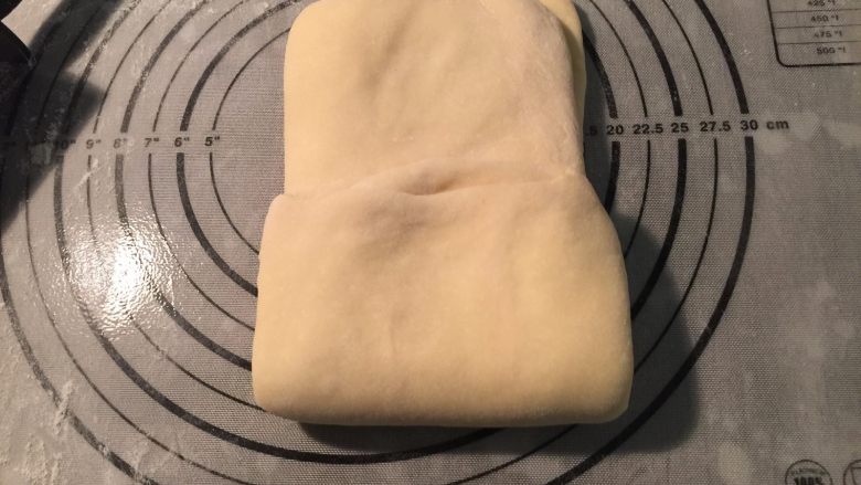起酥手撕包,用擀面杖把包好黄油的面片，擀开成长方形薄面片，从面片的一端1/3向中间翻折，另一端也从1/3处向中间翻折。这是第一次三折；再用擀面杖擀开三折