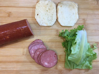 童趣早餐——乌龟全麦三明治,取出烤好的面包片，将火腿切成片，生菜叶切成面包片的大小。