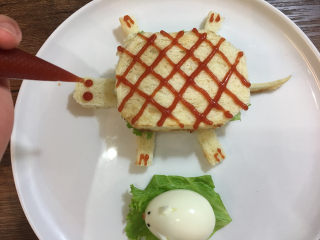 童趣早餐——乌龟全麦三明治,将番茄酱挤在一个裱花袋里，然后在乌龟的身体上画出花纹，点上眼睛和脚趾。