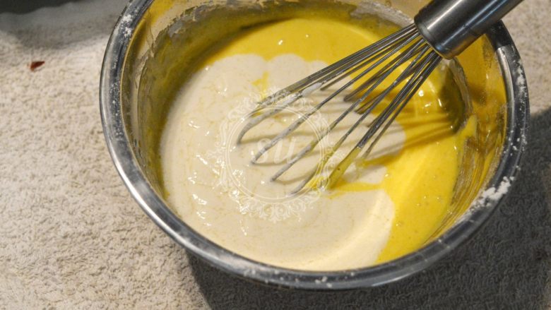 夏日清爽柠檬乳酪杯子蛋糕,混合搅拌均匀的两份面糊，倒在一起，混合均匀。这样把面粉分成两部分加入到液体材料中，能够最大限度的减少面粉颗粒，并且混合的更为均匀