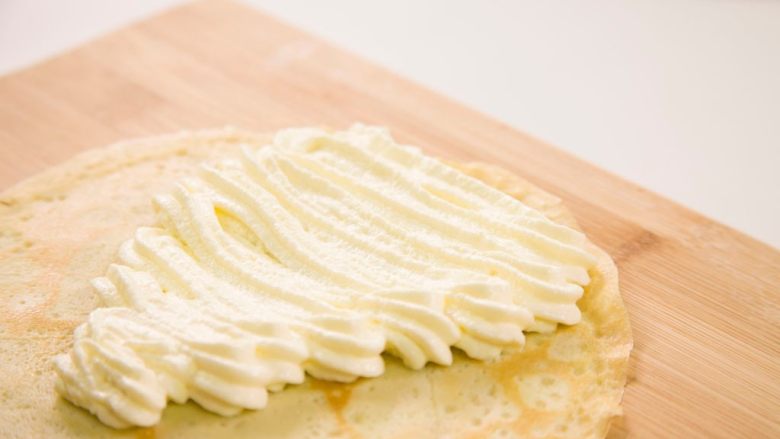 香蕉可丽饼,将淡奶油打发，在可丽饼皮上的一边挤上奶油。