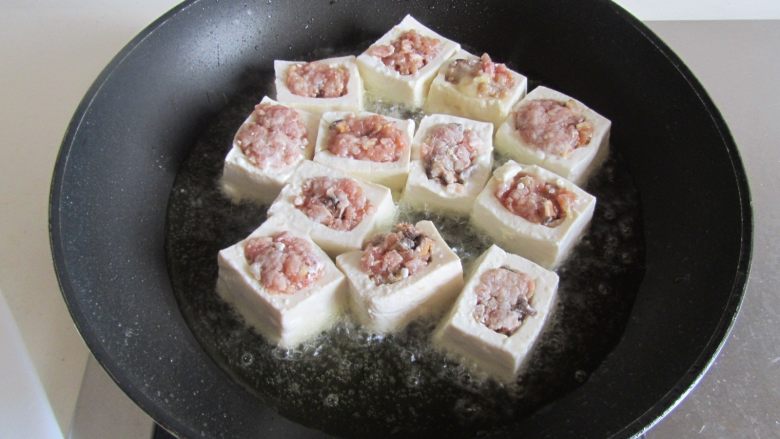 客家酿豆腐,热锅放入适量的油， 下入酿好的豆腐块里面去煎；