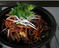 干锅茶树菇,将炒好的菜全部放进铁盘，并撒葱丝和香菜提味，趁热上桌，即可