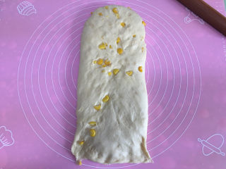 面包机版玉米吐司,发酵完毕后取出面团进行排气，然后揉圆，白擀成椭圆形，然后翻面，底部按薄。