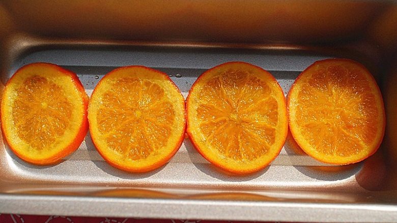 鲜橙磅蛋糕,从之前准备好的橙片糖浆中取出4片大小合适的橙片，放入模具中
