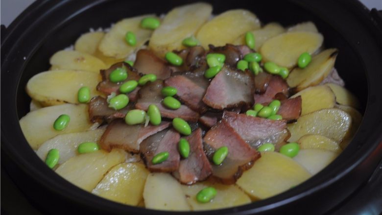 懒人餐，一锅出——腊肉排骨饭,将腊肉和排骨摆放在上面。盖上锅盖继续焖煮至完全熟透，撒上青豆粒即可。