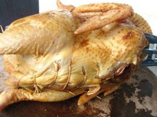 香茅烤全鸡,腌好的鸡取出，将一半的配料放进鸡肚子，再加入香菇和洋葱，塞满整只鸡肚子，将鸡固定好在烤架上，再用线缝好鸡肚子。用锡纸包住一下鸡尖翅的位置