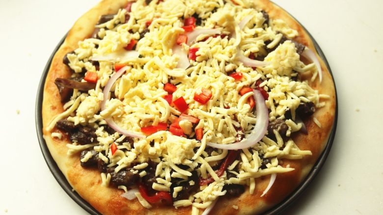 黑椒牛柳披萨,再铺上一些奶酪，表面撒一些青红椒做装饰。