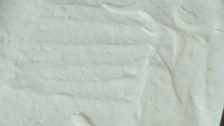 QQ糖抹茶慕斯,蛋白糊和蛋黄糊混合均匀，倒入不粘烤盘中，用刮刀抹平表面。（不粘烤盘里不需要垫油纸。）放入烤箱中，180度烤16分钟，烤至表面金黄。 