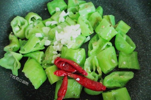 虎皮青椒炒鸡蛋,不断煎炒至泛黄起皮。 用余油煸香蒜末、干辣椒，继续翻炒。