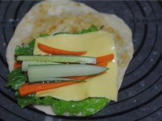 快手蔬菜卷饼,饼上面刷上豆瓣酱，摆上生菜和奶酪片、黄瓜条、胡萝卜条