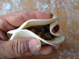 柳叶三鲜蒸饺,
用中指把面皮按向馅料方向，用手捏挤，然后用大姆指和食指托起两旁的面皮，只其形成W形。