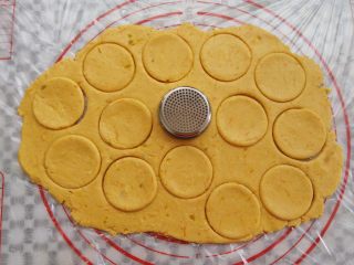 万圣节不给糖就捣蛋——南瓜饼干,南瓜面团擀成一个大面饼，用一个大的圆形工具印出饼干胚
