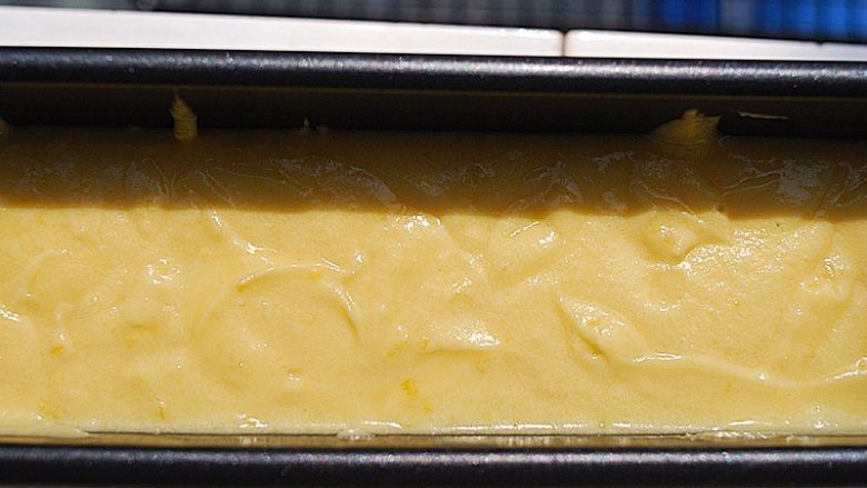 柠檬磅蛋糕,倒入磅蛋糕模具中，用勺子将蛋糕抹成中间凹两边高