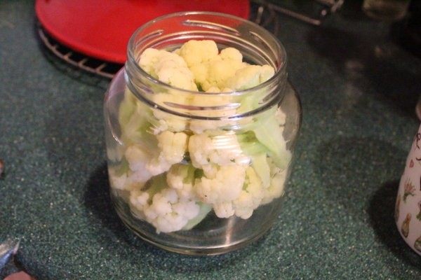 腌渍花椰菜,趁瓶子尚热将花椰菜和洋葱放入玻璃瓶中，不要硬塞，以保持花椰菜形状。