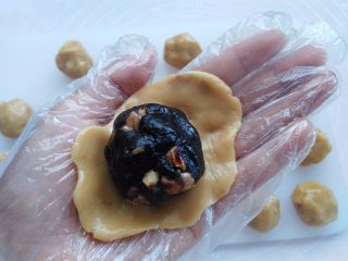 核桃枣泥月饼,戴上一次性手套，取其中一个面团用2个掌心的摩擦力按扁，放上枣泥馅